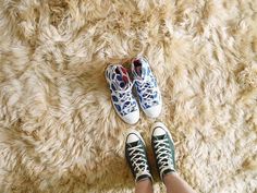 two pairs of tennis shoes sitting on top of a shaggy rug