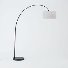 a black floor lamp with a white shade on the base and a round light fixture