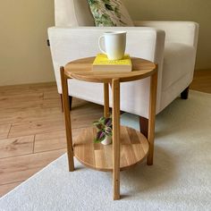 a small table with a cup on it in front of a white couch and chair