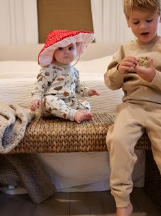 two toddlers sitting on a bed playing with each other