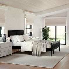 a bedroom with white walls and wood flooring, along with a large bed in the center