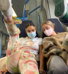 two women sitting on a train wearing face masks