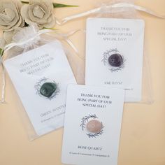 two thank you cards and one stone brooch are sitting on a table next to some flowers