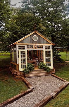 a small wooden shed sitting on top of a lush green field