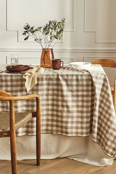 a dining room table with a checkered table cloth on it and two wooden chairs