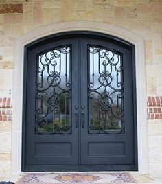 a dog laying on the ground in front of a black door with wrought iron doors