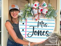 a woman holding up a sign that says mrs jones on the side of her house