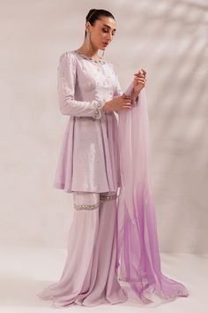 Pakistani Eid Dress in Lilac Gharara and Peplum Style is a stunning masterpiece that will give you a head-turning look on the festive occasion. This beautiful Gharara Dress is embellished with crystals, Resham, and sequins, making it an epitome of beauty and grace. Detailed Description: SKU: PS1831 Detailing: Embroidery, Threads, Crystals, Resham, Sequins Color: Lilac Fabric: Raw Silk, Organza Design: Fully Embroidered dress Event: Festive, Party wear Hand Embellished Organza Sharara For Diwali, Organza Dresses Hand Embellished For Diwali, Diwali Hand Embellished Organza Dresses, Diwali Hand-embellished Organza Dresses, Diwali Hand Embellished Georgette Sharara, Purple Embellished Sharara For Eid, Purple Organza Dress For Eid, Elegant Purple Organza Anarkali Set, Embellished Purple Sharara For Eid