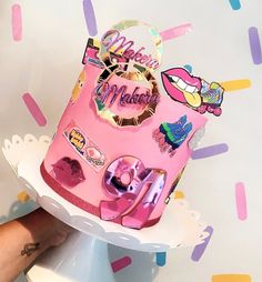 a pink birthday cake with lots of stickers on it