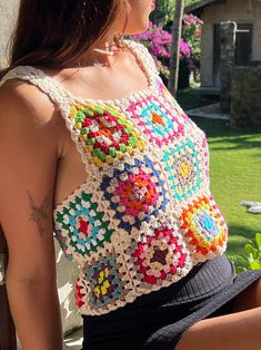 a woman wearing a crocheted top sitting on a bench