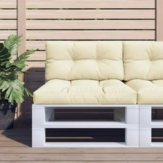 a white couch sitting on top of a wooden floor next to a potted plant