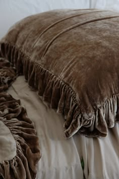 a close up of a pillow on a bed with ruffles and pillows in the background