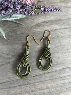 the earrings are made out of green leather and gold - plated brass hooks, with an intricate knot on each end