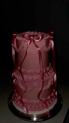 a three tiered cake with red ribbons on it's side, sitting on a black plate