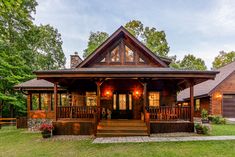 a small wooden house with porches and lights on