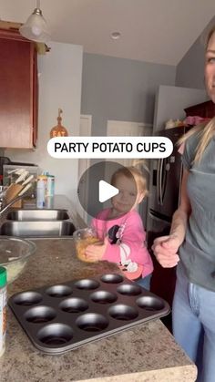 a woman standing next to a baby in a kitchen with muffin tins on the counter