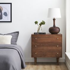 a bedroom with a bed, nightstand and pictures on the wall above it is shown