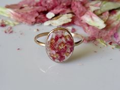 a close up of a ring on a table with flowers in the background and petals scattered around it