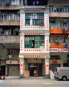 an old building with chinese writing on the side of it and a van parked in front