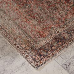 an antique rug is laying on the floor in front of a marble wall and floor