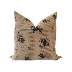 a beige pillow with black and pink flowers on the front, against a white background