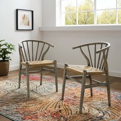 two chairs sitting on top of a rug next to a potted plant in front of a window