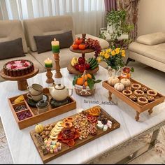 a table filled with trays of food on top of a white tablecloth covered floor