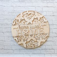 a wooden plaque with the words home sweet home surrounded by butterflies on a white brick wall