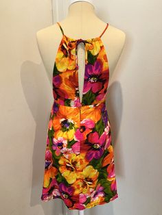 "Original to the 60s. Fab MINI Dress!! Bright bold floral pattern. Front cut out detail at chest, toe back neck, hidden back zipper and button closure. Mannequin is a US Size 4, and the dress fits her like a glove, for your sizing reference. Measurements laying flat - The high waist is empire style and hits just below the bust. Measures 13\" laying flat. Total length of dress is 31\" (mini dress) The halter style neck ties at back Tiki Time!" Fitted Halter Neck Floral Dress, Backless Floral Mini Dress For Garden Party, Fitted Multicolor Mini Dress With Tie Back, Retro Floral Print Knee-length Mini Dress, Retro Fitted Floral Print Mini Dress, Retro Knee-length Mini Dress With Floral Print, Retro Fitted Mini Dress With Floral Print, Retro Floral Print Party Dress, Retro Mini Dress With Floral Print