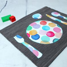 a placemat with a spoon and fork on it next to a wooden block toy