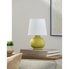 a green lamp sitting on top of a table next to a book and plant in a living room