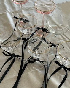 four wine glasses sitting on top of a table with black ribbon around the rims