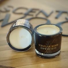 two candles sitting next to each other on a wooden table in front of a sign