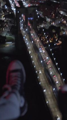 an aerial view of a city at night with cars driving on the road and lights in the street