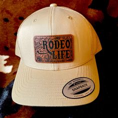 Tan “Rodeo Life” Leather Patch Cap! * 65% Polyester, 35% Cotton *6-Panel, Structured, Hard Buckram Backed Front Panels * Matching Undervisor (Camo And Multicam Have Black Undervisor) * Matching Snapback Closure * 3 1/2" Mid-Profile Crown * 8-Row Stitching On Visor * Permacurv Visor * Measurements (In Inches) One Size Hat Band 24 Crown Height 3 ½ * Adult Unisex Retro Trucker Cap Hat With Leather Patch, Leather Patch Ideas, Olive Green Hat, Balenciaga Hat, Prada Hat, Diy Hats, Hat Bar, Cattle Brands, Rodeo Life