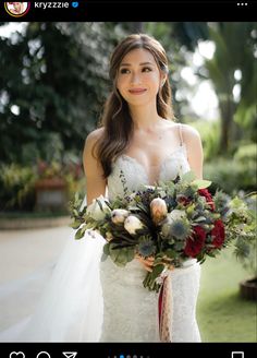 a woman in a wedding dress holding a bridal bouquet and smiling at the camera