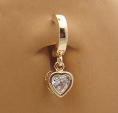 a gold heart charm hanging from a hook on a brown surface with a white diamond in the center