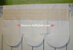 three white curtains hanging from the side of a wall with lace trimmings on them