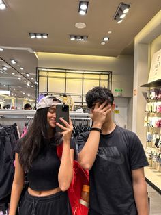 a man and woman taking a selfie in a clothing store