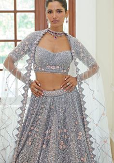 Step into elegance with this exquisite Silver Grey Bridal Lehenga Set. The silver grey satin choli is a masterpiece, embellished with shimmering silver beads, sequins, metallic accents, and sparkling crystals. Delicate 3-D rose pink florets add a touch of romance to the ensemble. The graceful silver grey net lehenga flows beautifully, while the matching net dupatta adds a final touch of sophistication. Perfect for the discerning bride who wants to make a statement on her special day. Composition : Blouse-Satin, Lehenga and Dupatta- Net Care: Dry Clean Only and Vacuum Storage This product can be customized for sleeves, length of blouse and neckline Delivery : 6-8 weeks as the product is hand crafted. Check Size Guide or choose MySize for free customisation (All Sizes above XL can be made at Grey Bridal Lehenga, Satin Lehenga, Blouse Satin, Bridal Lehenga Red, Vacuum Storage, Net Lehenga, Indian Wedding Wear, Satin Blouses, Net Dupatta