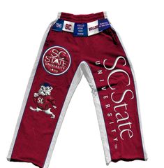 Celebrate the pride and legacy of South Carolina State University with the SC State Tag'Em Up Pants. These sweatpants are designed for Bulldogs who want to showcase their school spirit in style and comfort. Crafted from premium fleece cotton, the pants feature bold garnet side panels and white piping that represent the university’s iconic colors. The puff screen print logos on both legs highlight SC State’s Bulldog mascot and other key emblems, making a statement wherever you go. Perfect for gam Collegiate Cotton Activewear For Streetwear, Cotton Sports Bottoms With Team Spirit Style, Collegiate Style Cotton Sweats For Loungewear, Sportswear Style Cotton Joggers, Cotton Athleisure Pants For Sports Events, Collegiate Cotton Bottoms For Streetwear, Cotton Joggers For Streetwear Sports Season, Sporty Cotton Joggers For Sports Events, Team Spirit Cotton Bottoms For Sports Events