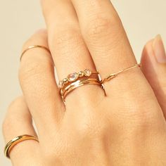 a woman's hand with two gold rings on top of her finger and the other ring