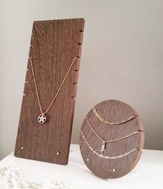 two necklaces are on display next to a wooden stand