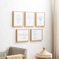 four framed hot air balloons on the wall above a crib