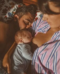 a man and woman laying in bed with a baby