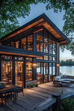 a house that is sitting on top of a wooden deck next to the water and trees