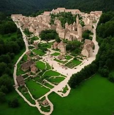 an aerial view of a village in the middle of a green field with lots of trees