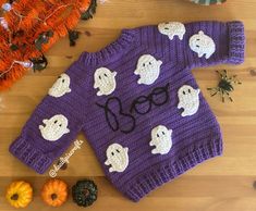 a knitted sweater with ghost faces on it next to pumpkins and other decorations