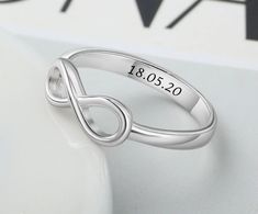 a white gold ring with an engraved date on the side and a heart in the middle