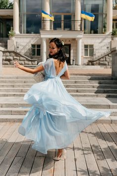 a woman in a blue dress is walking down some steps with her hands out to the side